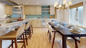 A modern kitchen with a marble countertop, wooden chairs, and a dining table set for six. - JHRL - Wind River #2, Well-Appointed and Well-Located - 1 minute from Ski Access (Teton Village)
