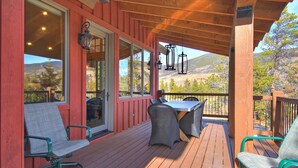 Une terrasse extérieure couverte, dotée d’une table et de chaises, qui offre une vue sur un paysage montagneux.