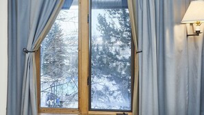 A room with a large window, curtains, and a wall-mounted lamp. - JHRL - Rendezvous D4, Great location for families (Teton Village)