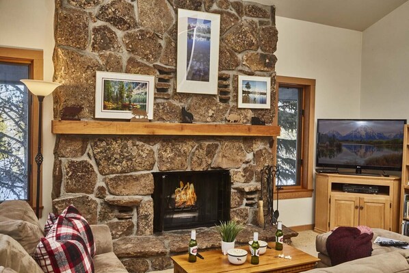 A cozy living room with a stone fireplace, a flat-screen TV, and a comfortable couch. - JHRL - Rendezvous D4, Great location for families (Teton Village)