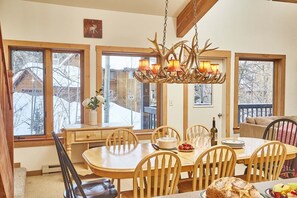 A dining area with a wooden table, chairs, and a chandelier with antler decorations. - JHRL - Rendezvous D4, Great location for families (Teton Village)