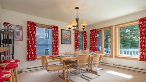A dining area with a wooden table, metal chairs, red curtains, and a chandelier.