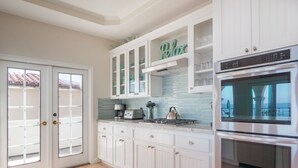 A kitchen with white cabinets, a built-in oven, and a coffee maker.