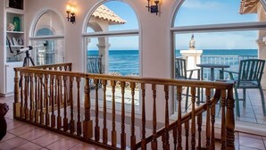 A balcony with a wooden railing, a telescope, and a view of the ocean.