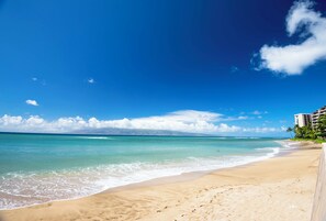 Une plage avec une eau d’un bleu limpide et un rivage sablonneux.