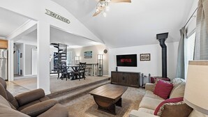 Una sala de estar moderna con chimenea, televisor y una escalera que conduce a un comedor.