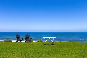 Relax in style with ocean views from this serene outdoor space, featuring Adirondack chairs and a picnic table.