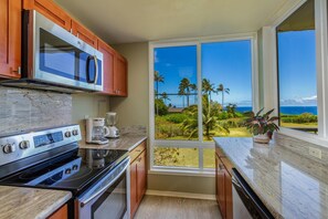 Enjoy a meal with a view of lush palm trees and a clear sky from this kitchen's large window.