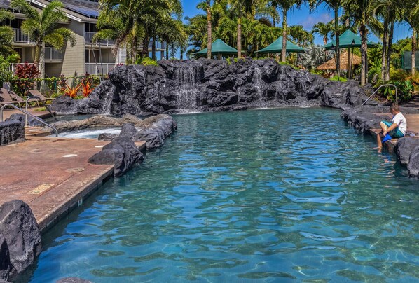 Relax by the tranquil pool surrounded by natural rock formations and lush tropical gardens.