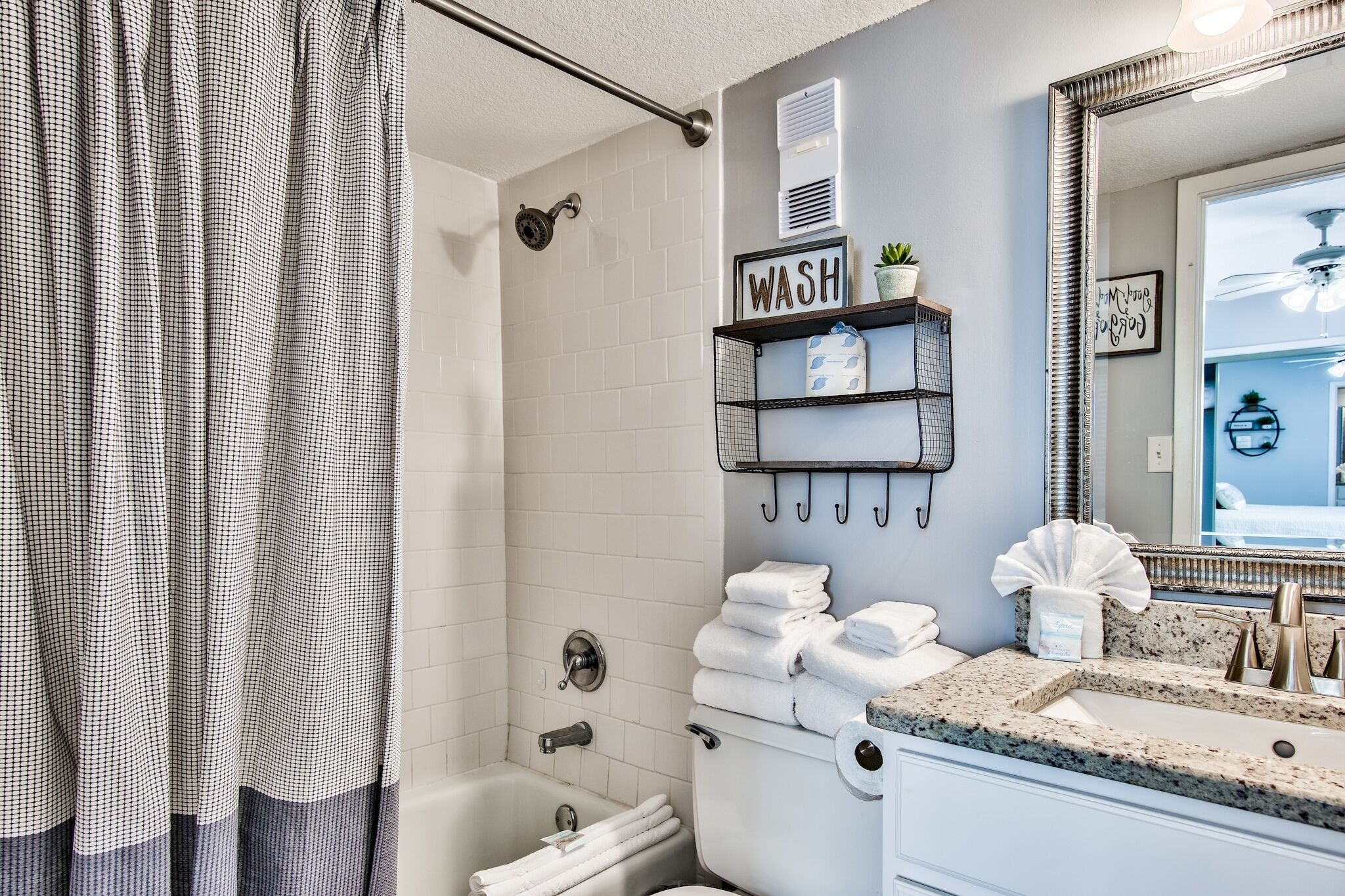 Une salle de bain comprenant une douche, des toilettes, un lavabo avec un miroir et un porte-serviettes avec des serviettes.