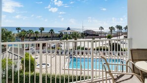 A pool area with lounge chairs and umbrellas, overlooking a beach and ocean. - 🌅 Islander #304 – Affordable Beach Getaway with Amazing Sunrises! 🌊✨ (Destin)