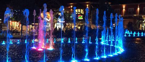 Une fontaine illuminée de couleurs bleues et roses, avec de nombreux jets d’eau, qui offre un spectacle nocturne.