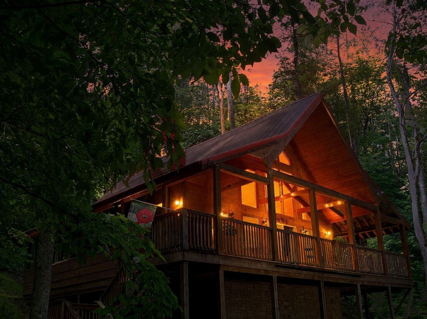 A wooden cabin with a balcony, surrounded by trees.