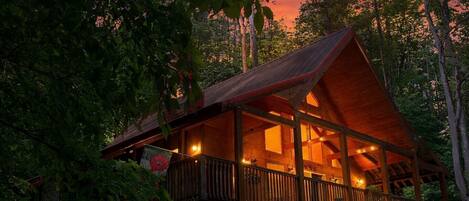 A wooden cabin with a balcony, surrounded by trees.
