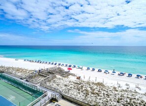 Ein Strand mit blauem Himmel, Sandstrand und Poolbereich.
