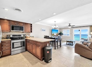 A modern kitchen with a large island, built-in microwave, and stainless steel oven.