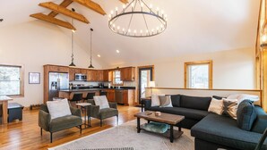 A spacious living area with a modern kitchen, wooden beams, and a chandelier. - Aussies Lookout - Panoramic Mountain Views, Hot Tub, Pool Table! (Blowing Rock)