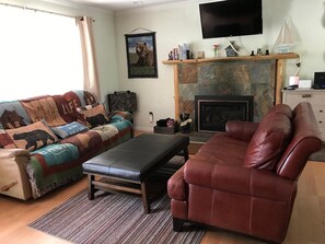 A living room with a fireplace, a television mounted above it, and a sofa with a matching ottoman.