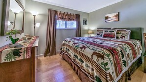 Una camera da letto con un letto, un comodino, una cassettiera, una finestra con tende e una lampada a parete.