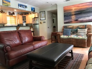 A living room with a brown leather sofa, a black ottoman, and a brown armchair with a cushion labeled 'CABIN SWEET'. - The Peace of Heaven Home Has Been Lovingly Set Up (South Lake Tahoe)