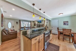 A spacious kitchen with a central island, wooden cabinets, and a dining area with a table and chairs.