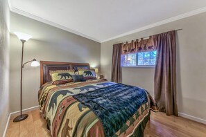 A bedroom with a bed, a floor lamp, a window with curtains, and a wall with a bear design.