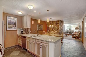 A modern kitchen with granite countertops, wooden cabinets, and a stone accent wall.