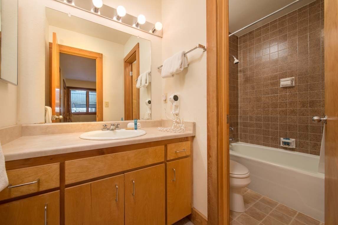 A bathroom with a sink, mirror, and a bathtub.
