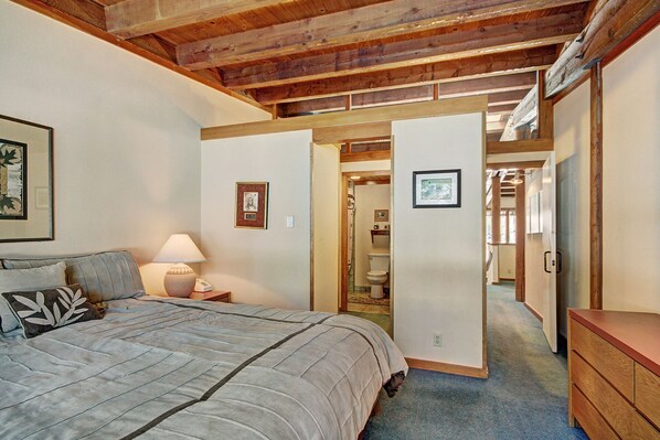 A bedroom with a bed, bedside lamp, and a wooden dresser.