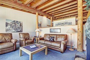 Una sala de estar acogedora con sofás de cuero, una mesa de centro y techo de madera.