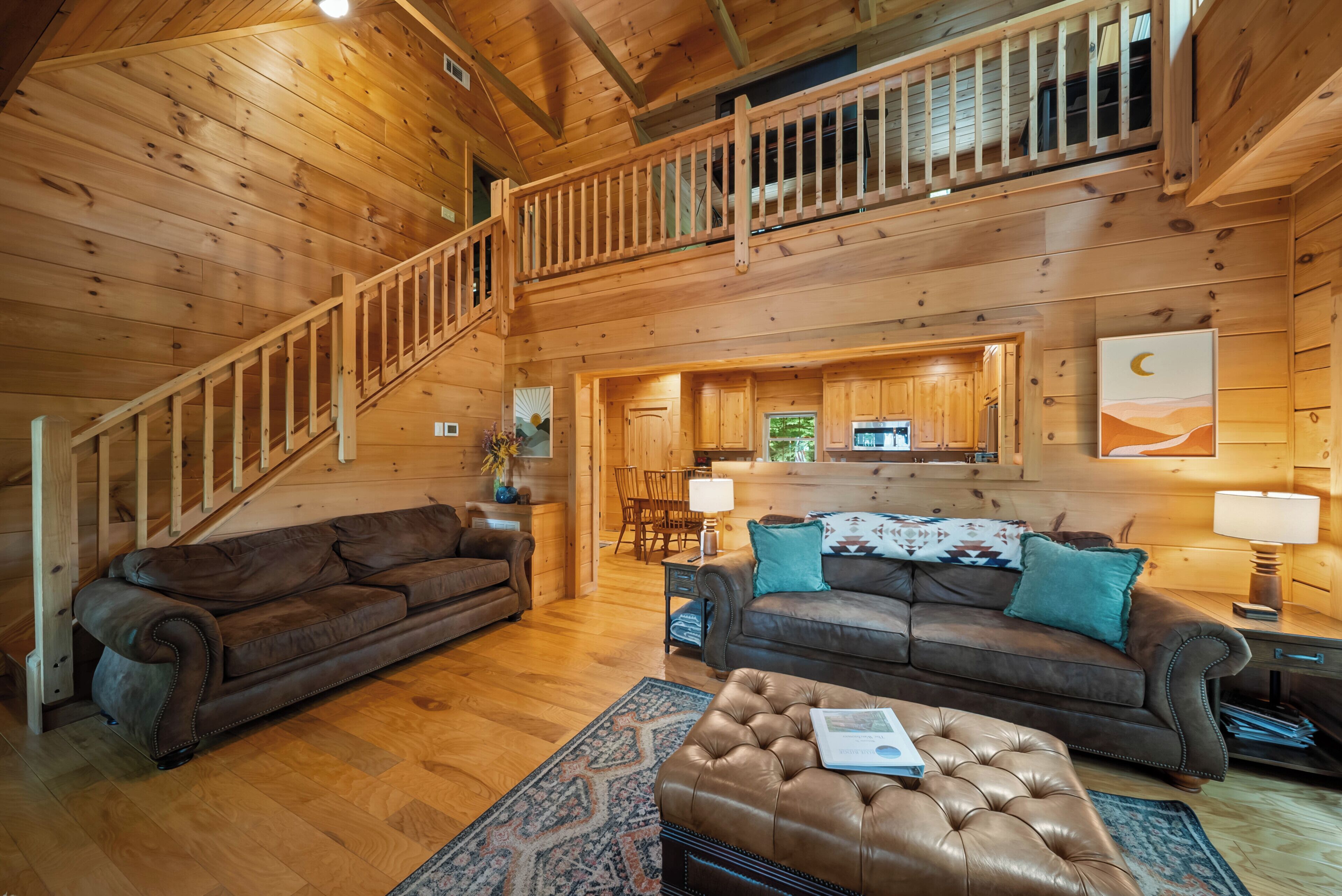 L’intérieur d’un chalet en bois comprend un escalier, deux canapés, une table basse et un coin cuisine.