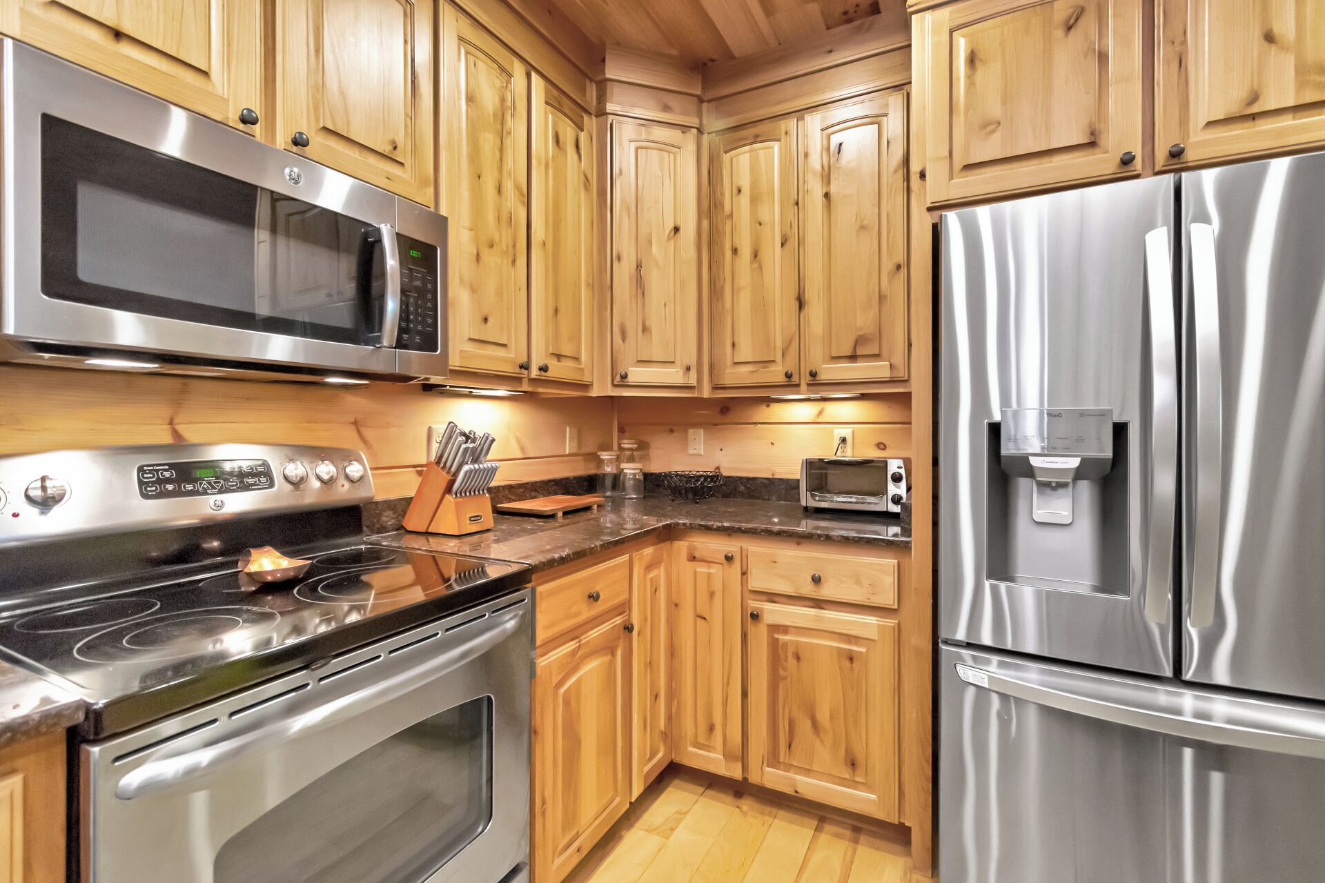 Eine Küche mit Holzausstattung, Edelstahlgeräten, darunter eine Mikrowelle, ein Backofen und ein Kühlschrank, sowie einem Wasserspender.