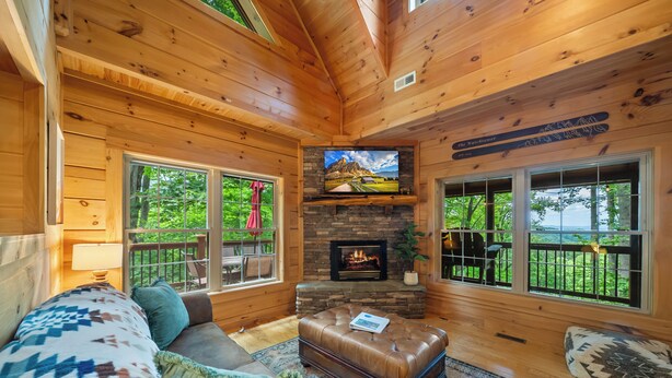 Ein gemütliches Blockhaus-Interieur mit Kamin, Holzwänden, einem Fernseher und einer bequemen Sitzecke.