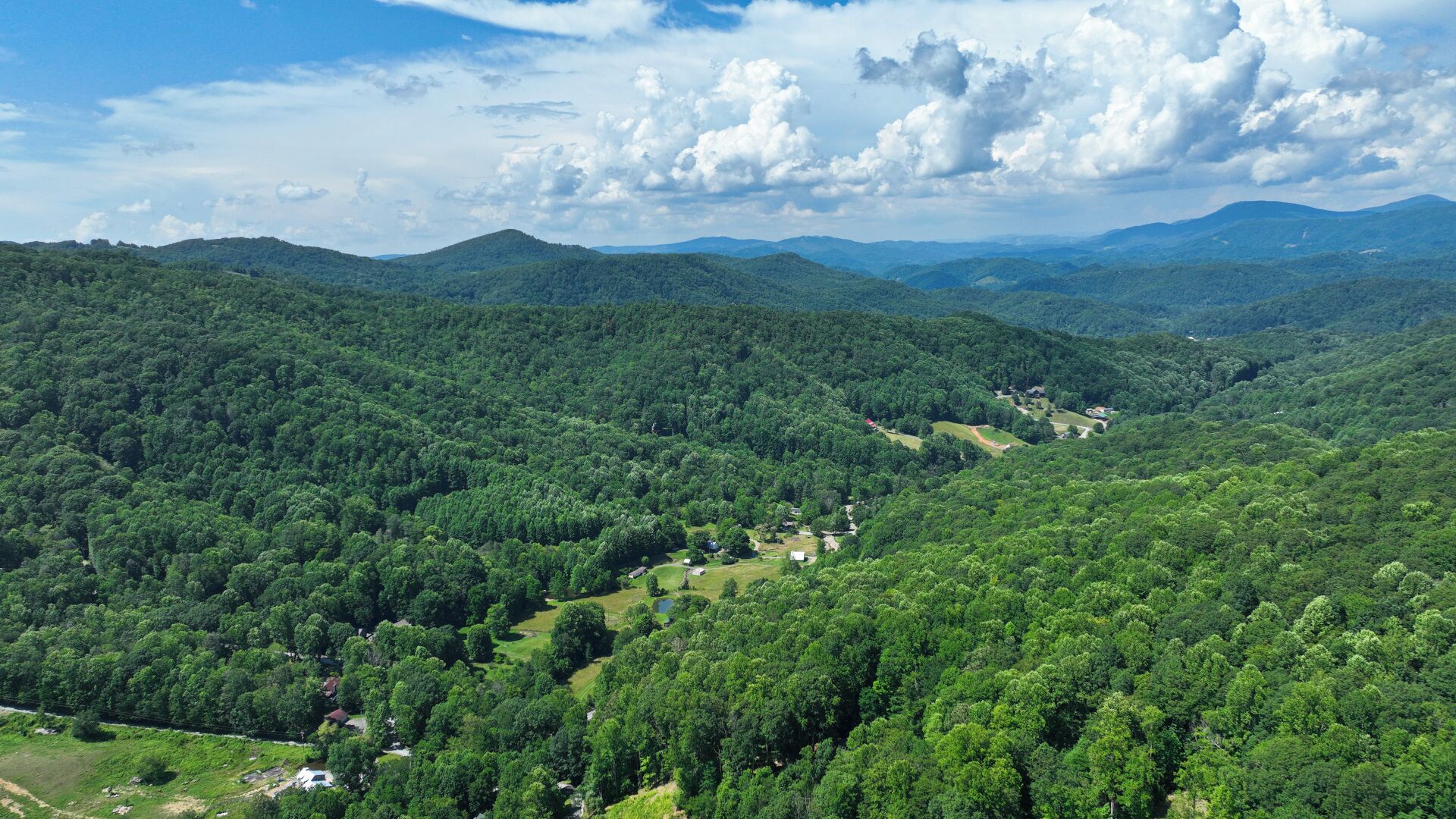 Un paysage montagneux caractérisé par une végétation forestière dense et la présence d’un petit village.