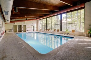 An indoor swimming pool with clear views of the outside through large windows, a wooden ceiling, and lounge chairs by the pool. - Ski Run Condo with Ski Run Views off deck, 3min walk to base, private entrance (Keystone)