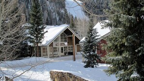 Una cabaña de montaña con techo nevado, fachada de madera y un letrero que dice "Mountain House".