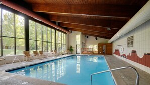 Una piscina interior con vistas despejadas a través de amplios ventanales, sillones de descanso y un mural en la pared.