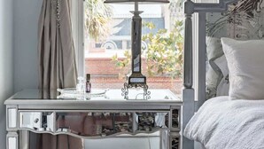 Une chambre à coucher avec un lit, un bureau avec une lampe, une chaise et une fenêtre avec des rideaux.