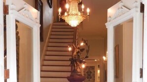 Un magnifique escalier, orné d’un lustre, avec des portes blanches et un plancher en bois.