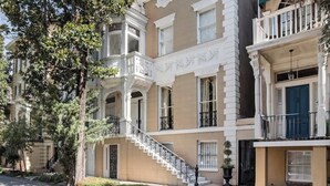 Un immeuble à plusieurs étages doté d’un escalier central, de balcons et d’un jardin bien entretenu.