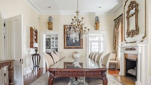 Une salle à manger élégante, avec une longue table, des chaises, un lustre et une cheminée.