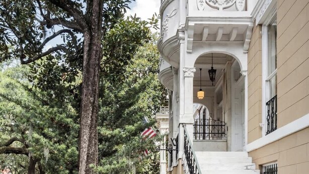 Un bâtiment doté d’un magnifique escalier, d’un trottoir bien entretenu et d’une végétation luxuriante.