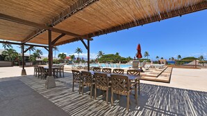 An outdoor seating area with tables and chairs, a pool, and palm trees in the background. - Ocean view, Top floor, Kaanapali Beach Resort, Golf Cart to Beach (Lahaina)