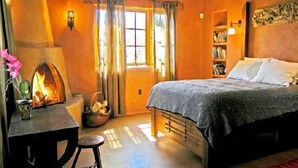 Een knus slaapkamer met een bed, een bureau en een open haard.