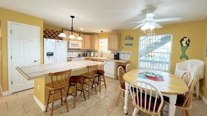 Une cuisine avec un îlot central, des chaises en bois, une table à manger et un ventilateur de plafond.