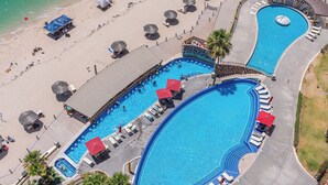 Ein Resort mit mehreren Schwimmbecken, Liegestühlen und Sonnenschirmen.