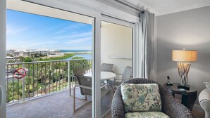 En balkon med udsigt over kysten, et spisebord og en sofa med en lampe.