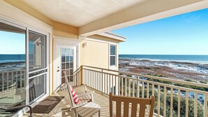 Een balkon met uitzicht op de oceaan en het strand.
