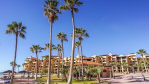 Un resort con edifici a più piani, palme e un cielo azzurro intenso.