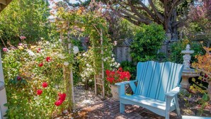 Un jardin avec un banc en bois et une variété de plantes à fleurs.